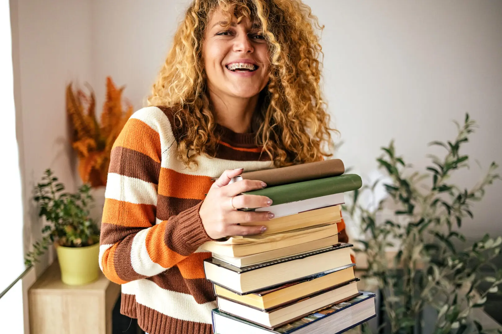 Curly-haired woman with books indoors